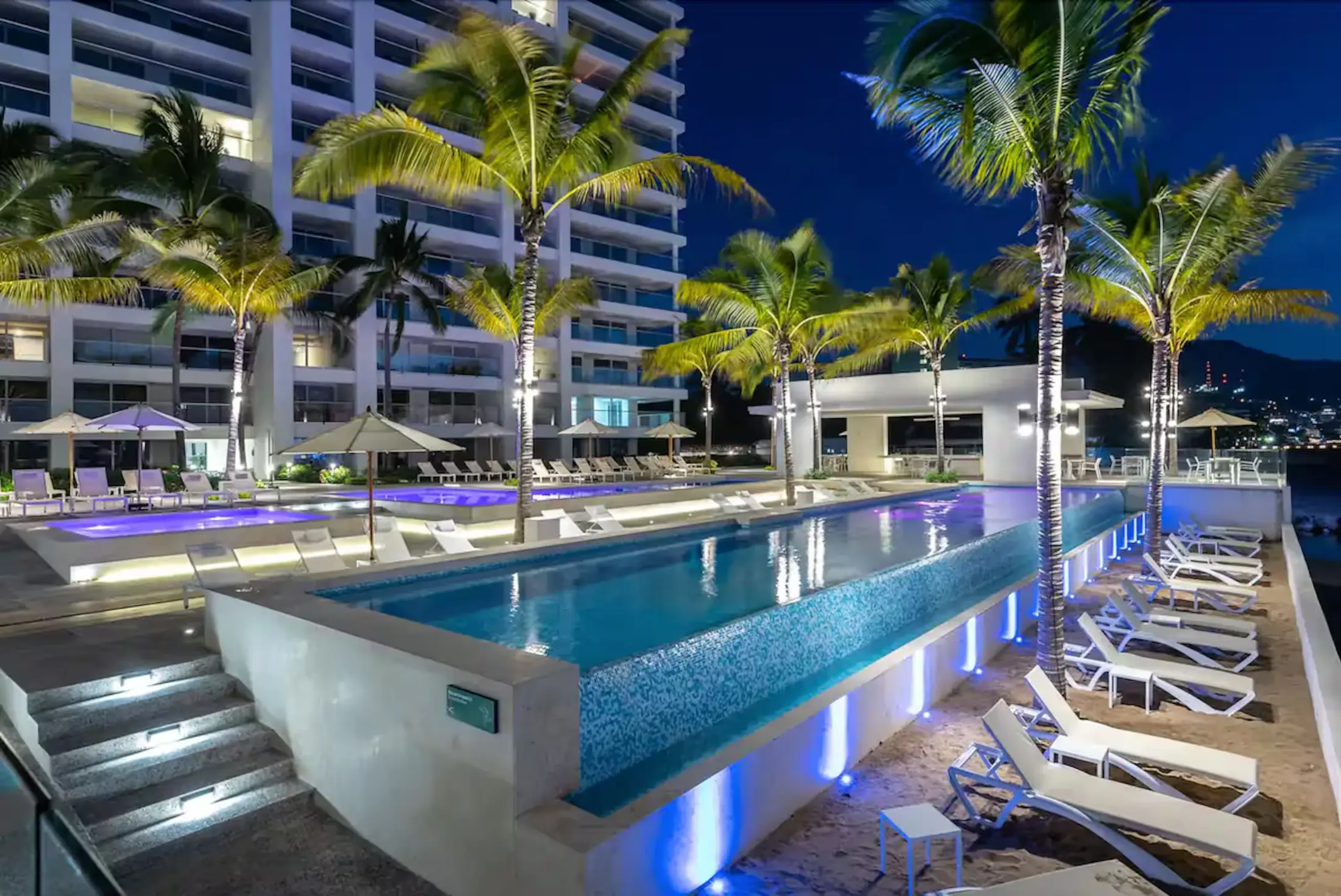 Beachfront pools illuminated after sunset